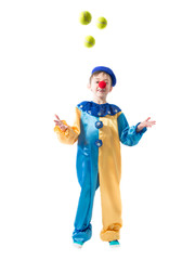 Little boy in clown suit juggling three balls and smiling on a white background