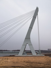 Obraz premium Big and new cable-stayed bridge hanging over the river on the background of buildings under construction and tower cranes
