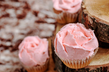 Cupcakes with pink cream on wooden background.
