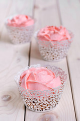 Cupcakes with pink cream on white background.