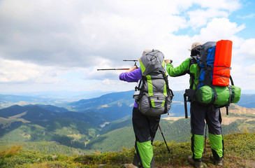 Couple of hikers showing the way with trekking poles up on the p