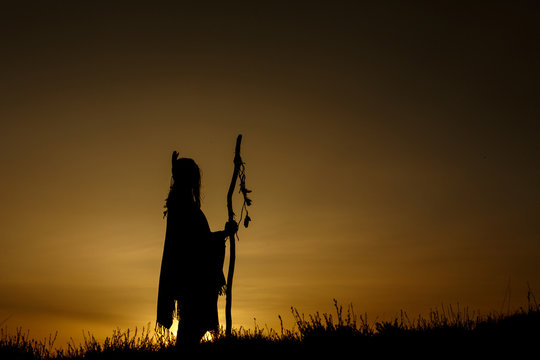 silhouette of boho shaman with pikestaff in sunset