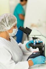 Naklejka na ściany i meble laboratory woman looking through a microscope