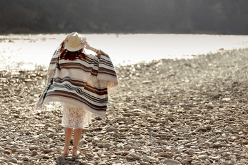 beautiful woman traveler wearing hat and poncho walking at river