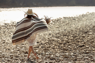 beautiful woman traveler wearing hat and poncho walking at river