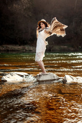 beautiful woman traveler standing on rocks in river and playing