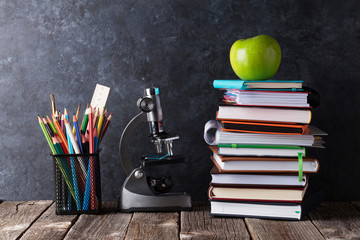 Notepads, supplies and apple in front of chalk board