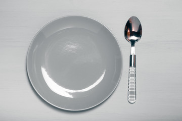 Plate and spoon  on a wooden background. Toned