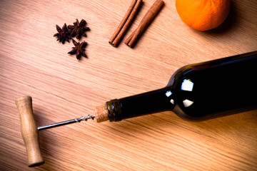 Fototapeta na wymiar Fresh orange, bottle of vine and spices on a light wooden table.