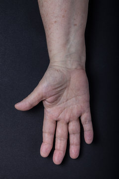 Hands of elderly woman on black background