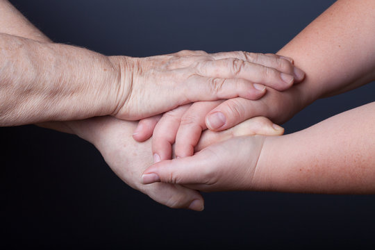 Hands of elderly and young women on black background