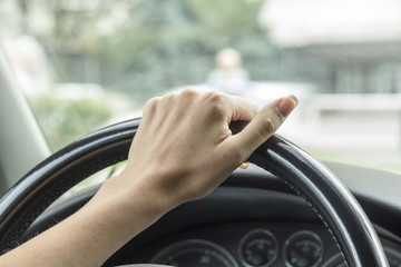 Arm girls with trendy manicure holds the steering wheel in the car. 