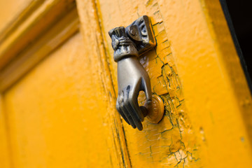 Door knocker knob closeup hand shape old vintage yellow orange bronze
