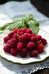 Ripe fresh organic raspberries on white plate