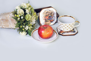 The red Apple lying on the dish and flowers.
