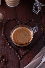 Black coffee among heart shaped coffee beans