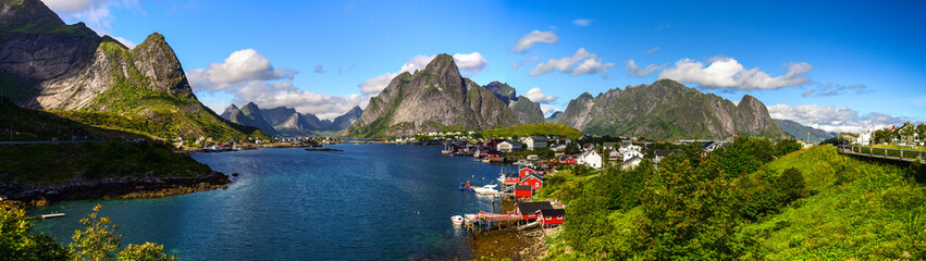 Fototapeta na wymiar Reine in Lofoten Islands, Norway, with traditional red rorbu huts under blue sky with clouds. 