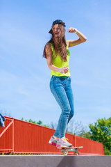 Teen girl skater riding skateboard on street.