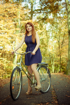 Redhead lady cycling in park.