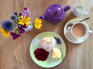 Traditional English afternoon cream tea with a scone, clotted cream, strawberry jam, a purple...