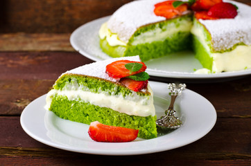 Green spinach cake with strawberry and mint on a dark rustic wooden background