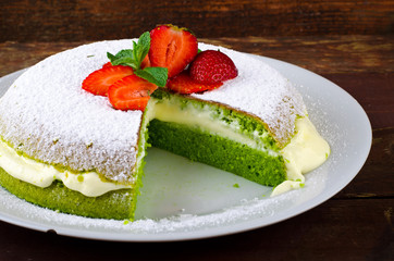 Green spinach cake with strawberry and mint on a dark rustic wooden background