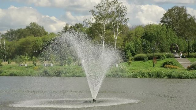 The fountain in the pond. The park with a lake, where a fountain.