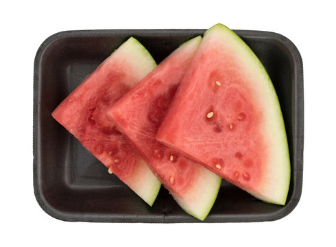 Slices of fresh watermelon on a black foam tray isolated on a white background.