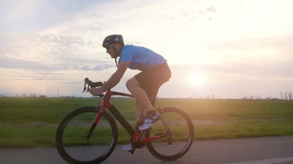 healthy man riding bike working out  training fitness outdoor backlit at the sunset  tracking shot from camera car 
