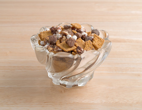 Smores candy mixture in a glass bowl atop a wood table.