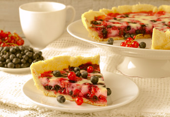 Mix berry tart, pie, cake with raspberries, bilberries, bluberries, red currant and cream on white background