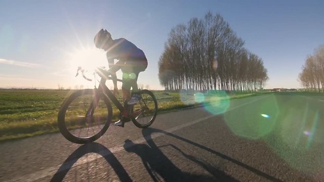 cyclist rides bike working out   drinking water while pedaling outdoor  tracking shot from camera car slow motion
