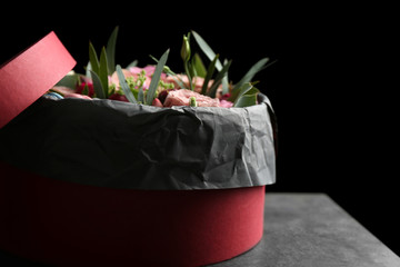 Box with fresh flowers and macaroons on black background