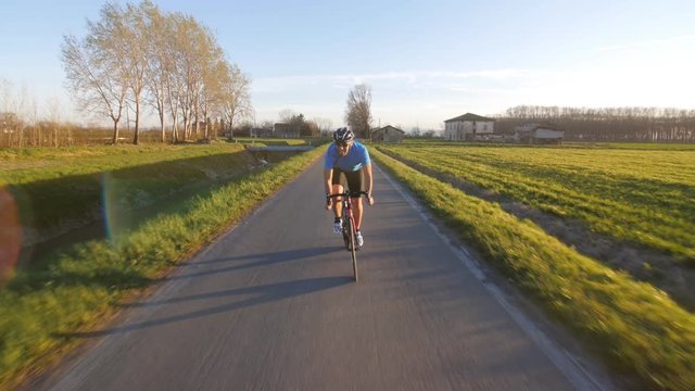 healthy man riding bike working out  training fitness outdoor at the sunset  tracking shot from camera car slow motion
