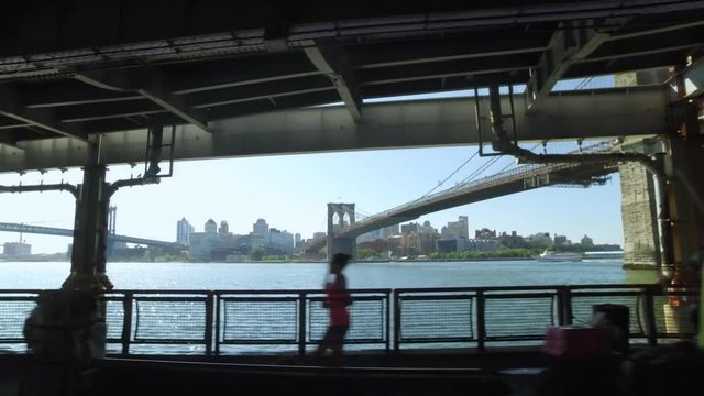 A profile view riding on the East River Bikeway with the Brooklyn Bridge in the distance.  	