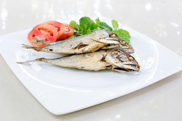 Fried mackerel with vegetable in white dish on tile plate