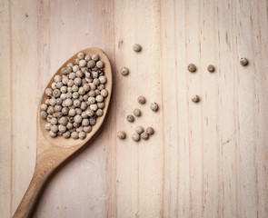 White pepper seeds in spoon on the wood table
