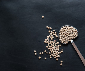 White pepper seeds in spoon on a black slate