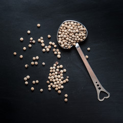 White pepper seeds in spoon on a black slate