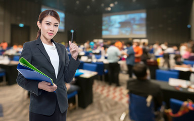 Beautiful asian working woman on the Abstract blurred photo of conference hall or seminar room with attendee background.