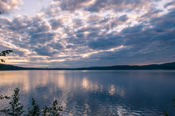 bright sunrise on the bank of forest lake