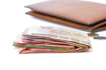 Thai cash with brown leather wallet behind on white background