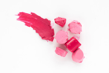Cut pink lipstick with smear of one, flat lay. Close-up of damaged female cosmetics, top view on colorful rosy rouge, copy space, white background