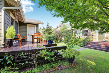 View of guest house with wooden deck and nicely trimmed garden