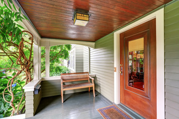 Cozy covered porch interior with wooden bench.