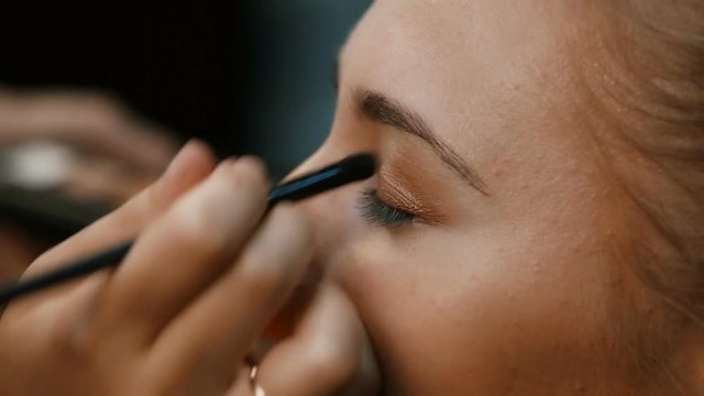 Eye makeup woman applying eyeshadow powder.Eyes Makeup.Make-up.Eyes shadows. Eye shadow brush.Make-up artist makes make-up of eyes of a young woman.Make-up artist with a brush for the face makes the