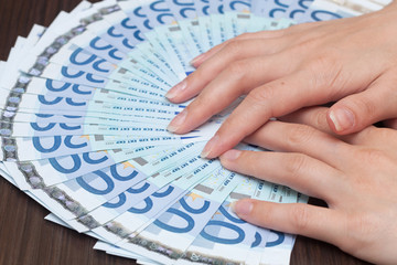 A woman is counting cash money, euro currency, dark background
