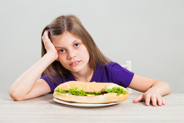 Little girl is unhappy because she has to eat sandwich for breakfast.
