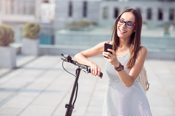 Cheerful woman standing near kick scooter
