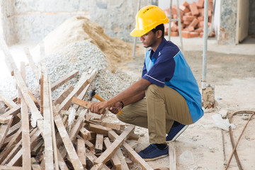 indian male contractor on site using hammer